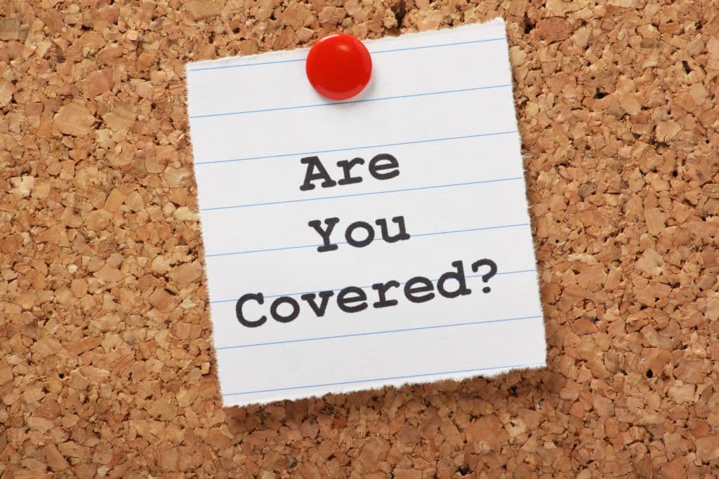 A note pinned to a corkboard with the text "Are You Covered?"