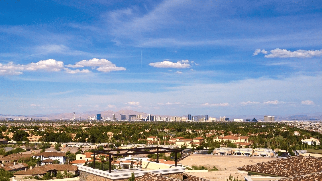 Spring Valley NV high risk insurance a vibrant image showcasing an expansive view of a cityscape with a clear blue sky above. The scene captures an urban area dotted with buildings against a backdrop of distant mountains, giving a sense of both the city's scale and its setting.