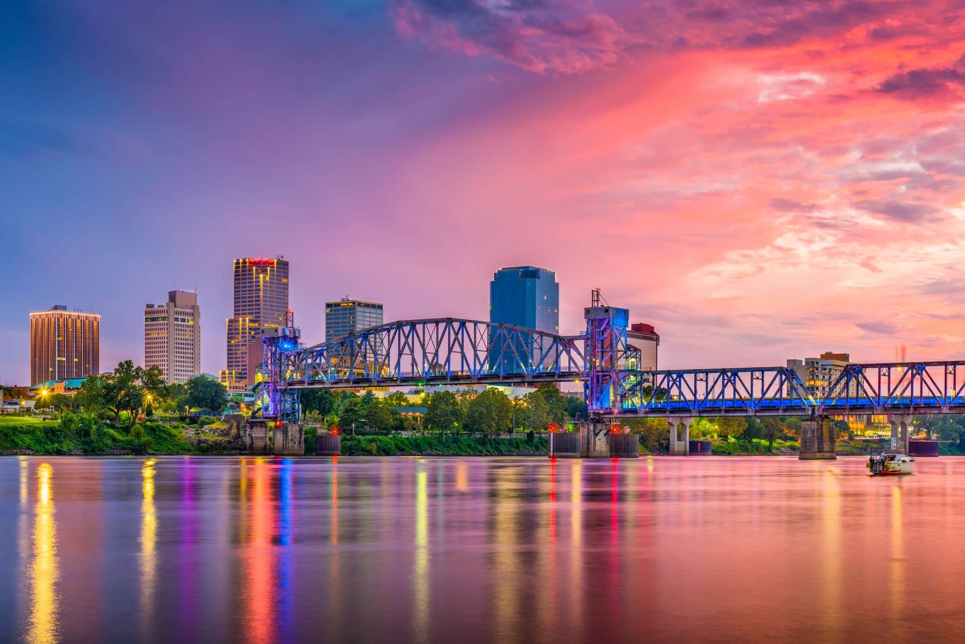 This is a beautiful image featuring a skyline with a bridge and water reflecting the colorful lights of the Little Rock Arkansas.